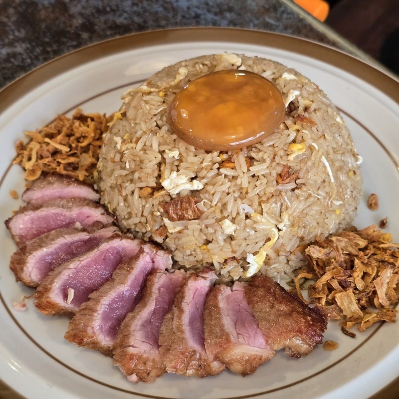 ข้าวผัดมันเนื้อโปะไข่แดงดอง เรียงเนื้อย่างสีชมพูและหอมเจียว
